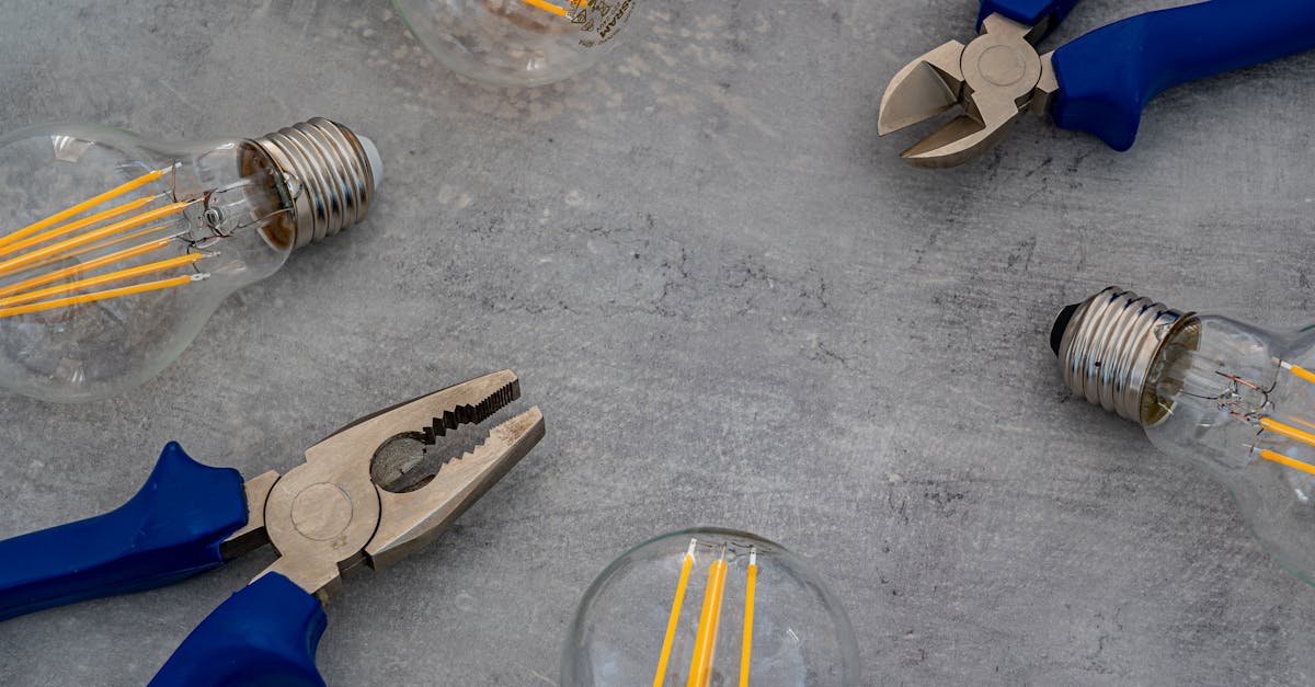 A flat lay of vintage Edison bulbs and pliers on a gray surface, emphasizing industrial design.